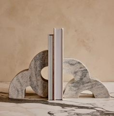 an open book sitting on top of a table next to a stone sculpture that looks like the letter q