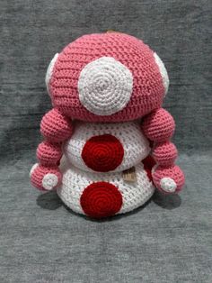 a crocheted stuffed animal sitting on top of a gray surface with red and white dots