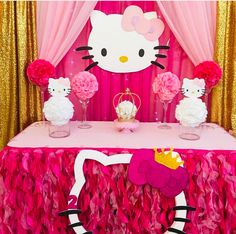 a hello kitty themed birthday party with pink and gold decorations, tissue pom poms