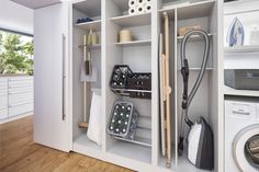 an organized laundry room with white cabinets and wood floors