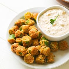 a white plate topped with tater tots next to a bowl of dip