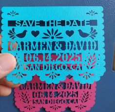 a hand holding up a blue and pink save the date card