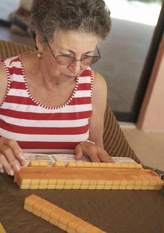 an older woman sitting at a table working on something