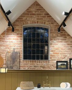 a bathroom with brick walls and exposed ceilings, including a window above the sink in front of it