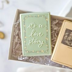 an open box with a book and some type of cake in it that says its a love story