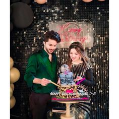 a man and woman standing in front of a cake