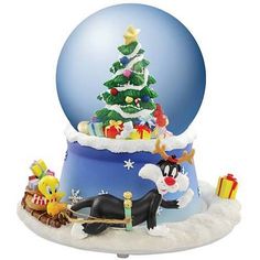 a snow globe with a christmas tree on top and presents in the bottom, as well as an ornament