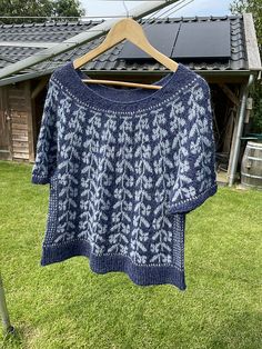 a knitted sweater hanging on a clothesline in front of a house with solar panels