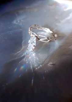 a diamond ring sitting on top of a shiny surface with the sun shining through it