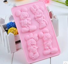 a pink tray with mickey and minnie mouse molds on white table next to flowers