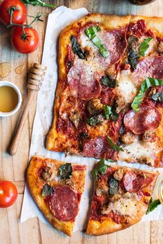 a pizza sitting on top of a wooden cutting board next to tomatoes and other vegetables