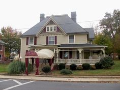 a large house with a covered porch in the middle of an intersection on a cloudy day