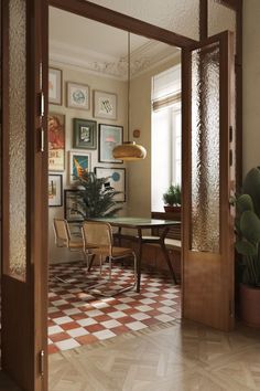 an open door leading to a dining room with pictures on the wall and potted plants