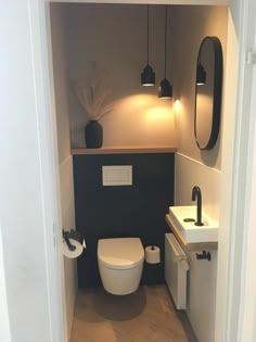 a white toilet sitting in a bathroom next to a sink under a mirror on the wall