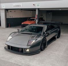 a black sports car parked in front of a garage with two other cars behind it