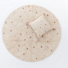 a round rug with pink dots on it and a white pillow sitting on top of it