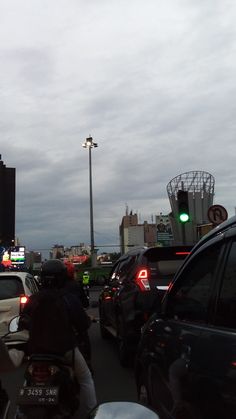 a group of people riding motorcycles down a street next to tall buildings and traffic lights