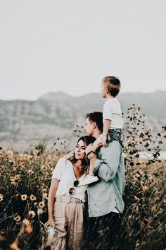 a woman and two children are standing in a field with wildflowers on the other side