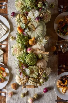 the table is set with many different types of food and dishes, including pumpkins