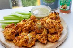 some fried food on a wooden plate next to celery and mayonnaise