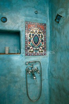 a bathroom with blue walls and a colorful tile design on the wall above the faucet