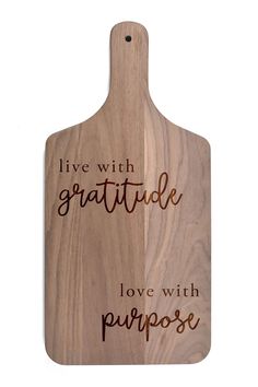 a wooden cutting board with the words live with grateful love with purpose written on it