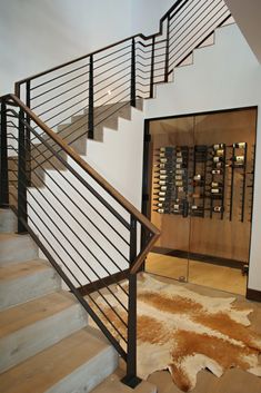 there is a stair case with wine bottles on the wall and carpeted flooring