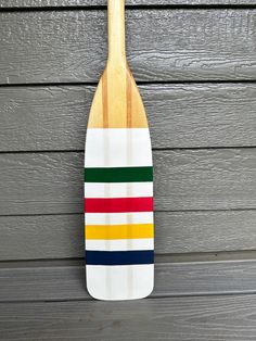 a wooden paddle board hanging on the side of a building with multicolored stripes