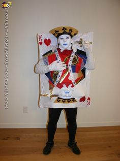 a man dressed up as a queen of hearts in front of a white wall and wooden floor