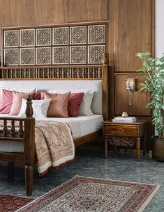 a bed sitting in a bedroom next to a wooden headboard and table with a potted plant on top of it