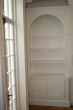 an empty white bookcase in the corner of a room