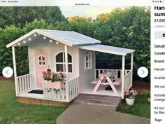 a small pink and white house with flowers on the porch, next to an advertise