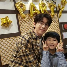 two young men standing next to each other in front of balloons and gold foil letters