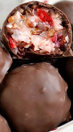 some chocolates are in a white bowl and one is cut open to show the inside