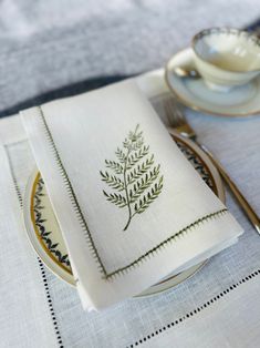 a white plate topped with a napkin next to a cup and saucer on top of a table