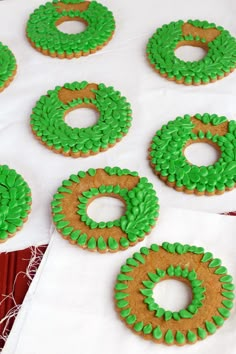 green and brown decorated cookies sitting on top of a white table cloth next to each other