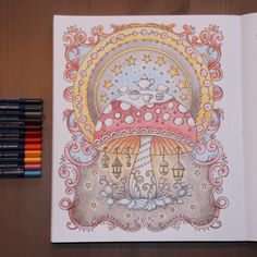 an open coloring book on a table with colored pencils