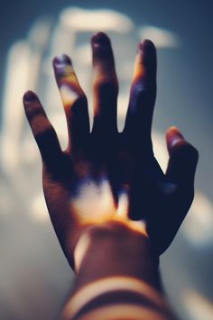 a person's hand with their fingers extended up in front of a blurry background