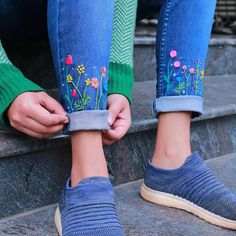 a woman is sitting on the steps with her feet up and wearing slippers that have flowers painted on them