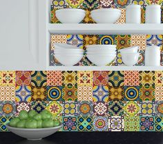 a bowl of green apples sitting on top of a counter next to plates and bowls