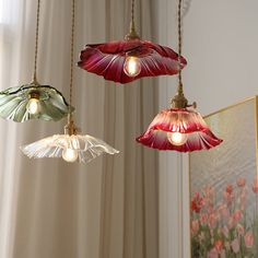 three lights hanging from a ceiling in a room with flowers on the window sill