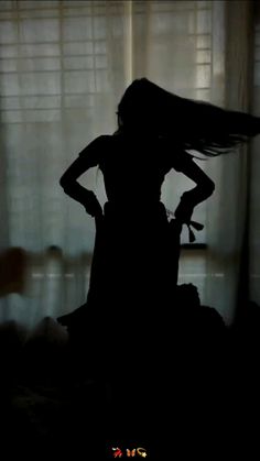 the silhouette of a woman standing in front of a window