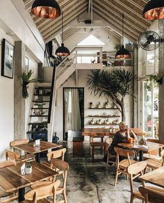 the inside of a restaurant with wooden tables, chairs and potted plants hanging from the ceiling