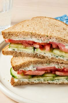 a cut in half sandwich sitting on top of a white plate next to a glass of water