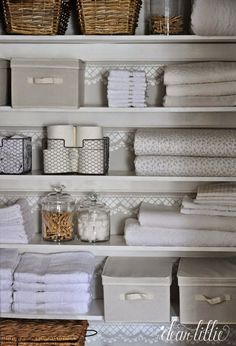 bathroom shelves filled with white towels and other items on top of eachother in glass jars