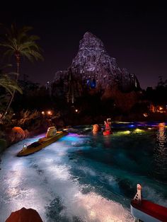 the water is blue and green as people are in small boats on it at night