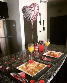 a valentine's day table setting with heart shaped balloons, pancakes and orange juice