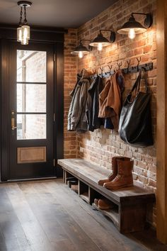 a brick wall with coat racks and boots hanging on it's hooks, next to a wooden bench