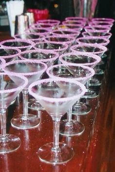 many wine glasses are lined up on the bar top, ready to be filled with drinks