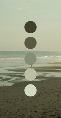 a person standing on top of a beach next to the ocean with circles hanging from it